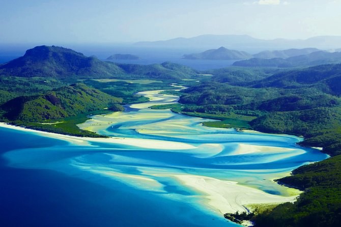 Hill Inlet from the air, white sand swirling through blue channels below the forested hills of Whitsunday Island