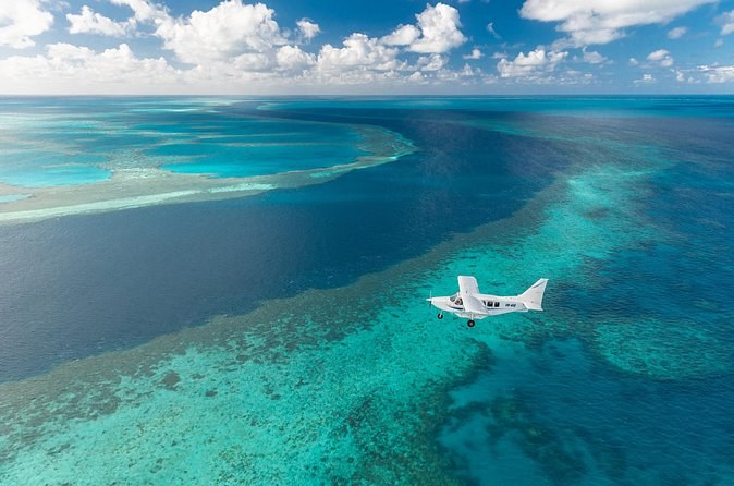 A small plane over reef flats and deep blue water far offshore